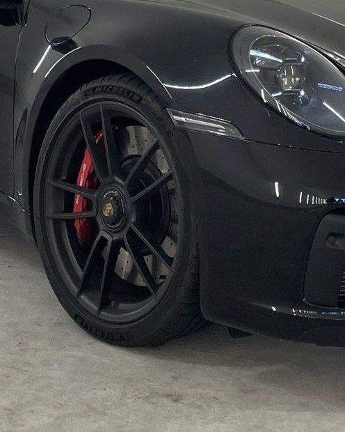 Front wheel and headlight of a black Porsche 911 Targa